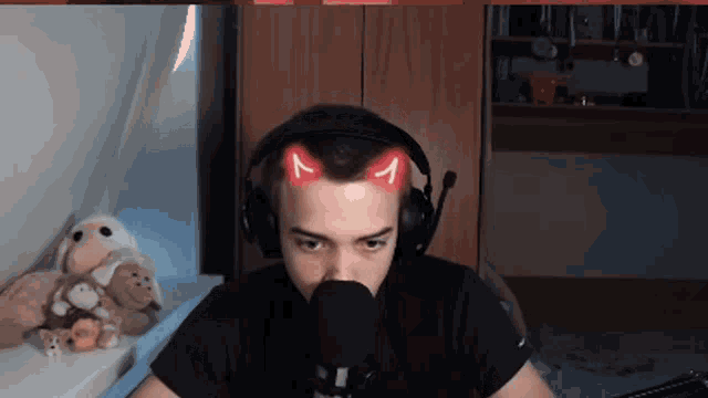 a man wearing headphones and a microphone has a cat ear sticker on his head