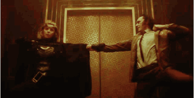 a man and a woman are standing next to each other in an elevator and shaking hands .