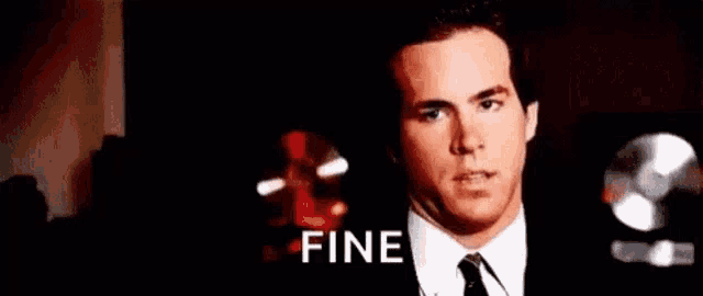 a man in a suit and tie is making a funny face and saying fine .