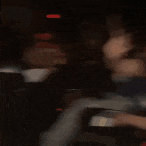 two people are sitting in a dark room and one of them is wearing a black shirt with the letter e on it