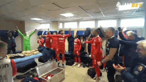 a group of soccer players in a locker room with a bet logo behind them