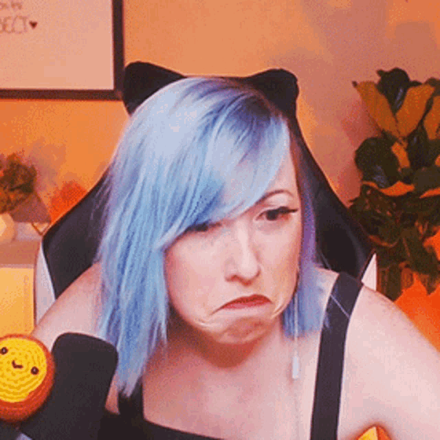 a woman with blue hair and cat ears making a face