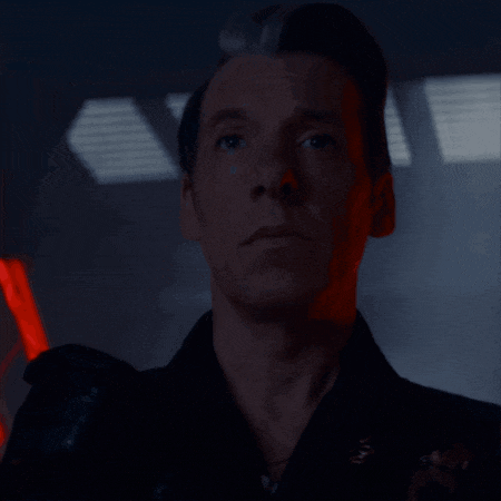 a close up of a man 's face in a dark room with a red light behind him