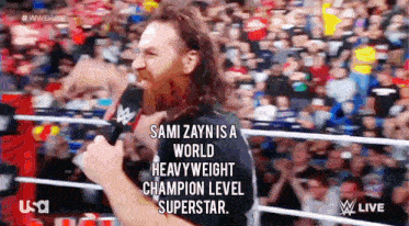a man with a beard is holding a microphone and talking into it
