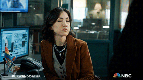 a woman sits at a desk with her eyes closed in front of a computer screen that says law and order on it