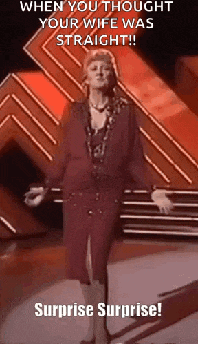 a woman in a red dress is standing on a stage with her arms outstretched and a surprise surprise .