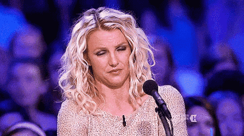 britney spears is making a funny face while speaking into a microphone .