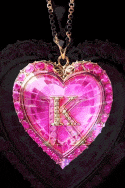 a pink heart shaped pendant with a letter k on it