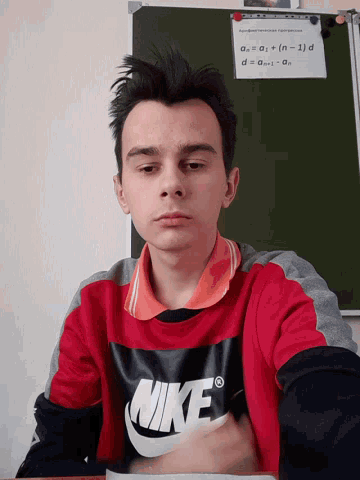 a man wearing a nike sweatshirt sits at a desk