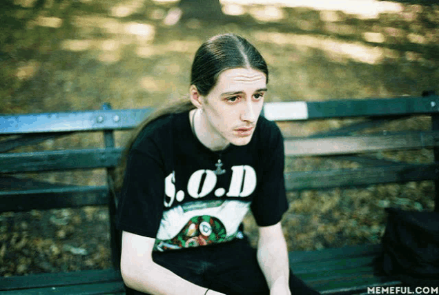 a man wearing a shirt that says s.o.d. is sitting on a park bench