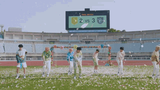 a group of young men are dancing on a field in front of a scoreboard that says final match 2 vs 3