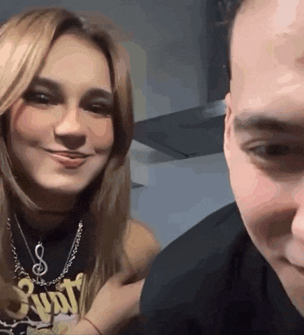 a man and a woman are looking at each other and smiling . the woman is wearing a necklace .