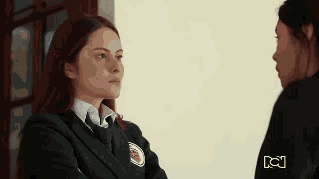 a girl in a school uniform talks to another girl with a rcj logo in the corner