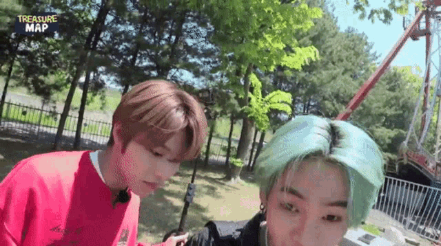 two boys with green hair are standing next to each other in a park .