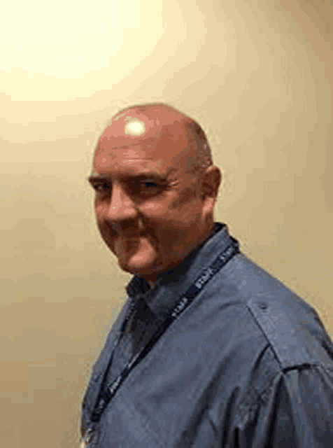 a bald man is wearing a lanyard around his neck and smiling .