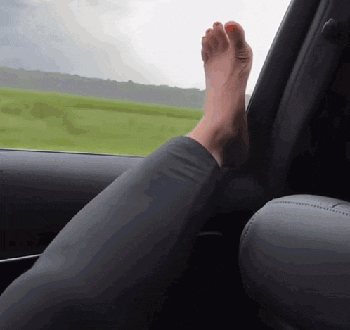a woman 's foot is sticking out of the window of a car