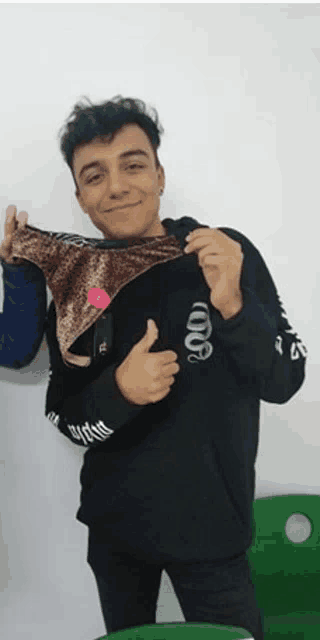 a young man wearing a black shirt with a snake on it is holding a pair of underwear
