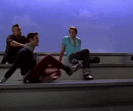 three men are sitting on a ledge with one wearing a blue shirt with the number 11 on it