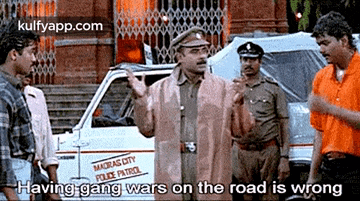 a group of men are standing in front of a police car talking to a police officer .