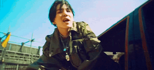 a young man in a green jacket is sitting in a car .