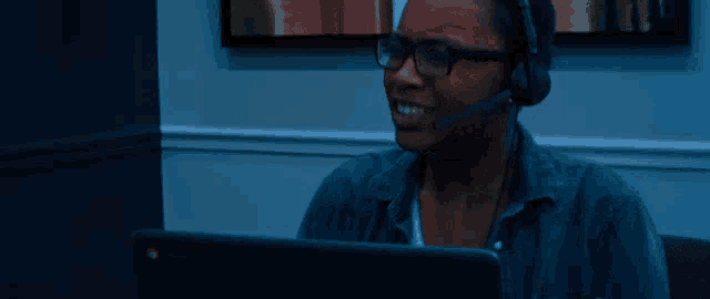 a woman wearing headphones and glasses is sitting in front of a laptop computer