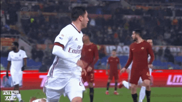 a soccer player wearing a white emirates jersey runs on the field