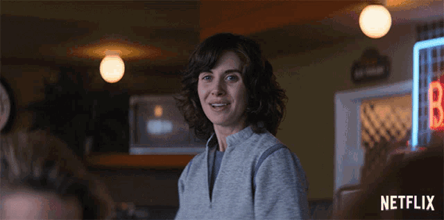 a woman is smiling in front of a neon sign that says netflix