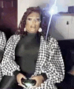 a woman in a plaid jacket is holding a video game controller and playing a video game .