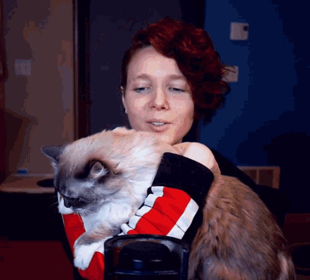 a woman is holding a cat in her arms