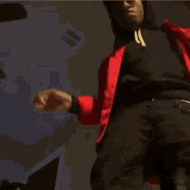 a man in a red jacket is smoking a cigarette in a dark room .