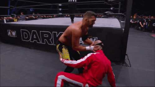 two men are wrestling in a ring that says dark on the side
