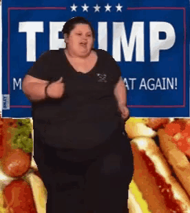 a woman is dancing in front of a trump sign and hot dogs