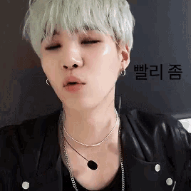 a man with white hair is wearing a black jacket and a necklace .
