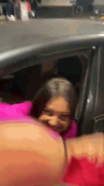 a woman in a pink sweater is sitting in a car