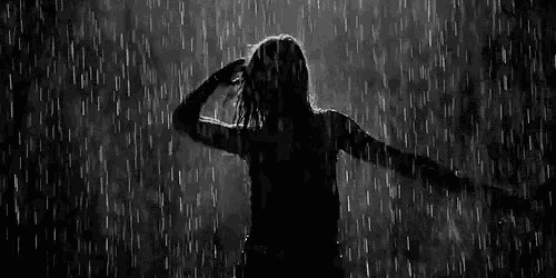 a black and white photo of a woman dancing in the rain .