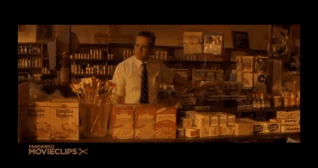 a man in a white shirt is standing in a dark room with a fandango movie clips logo in the corner .