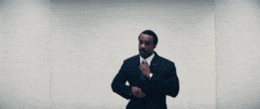 a man in a suit and tie is adjusting his tie