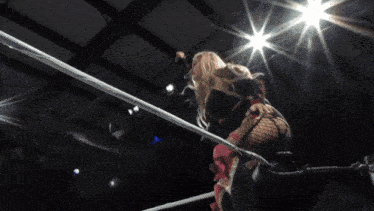 two women wrestling in a ring with one wearing pink