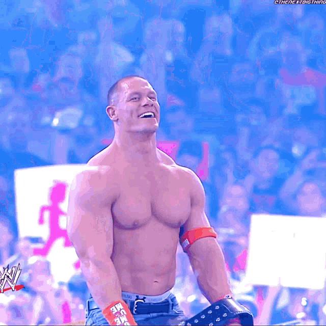a man without a shirt is smiling in front of a crowd and a sign that says ' the next trend ' on it