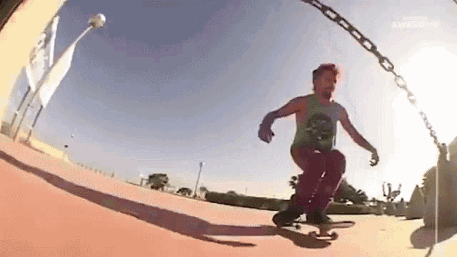 a man is riding a skateboard on a chain while wearing a green tank top