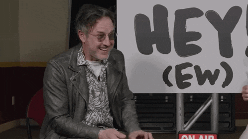 a man holding a sign that says hey ew