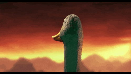 a goose with a yellow beak is standing in front of mountains