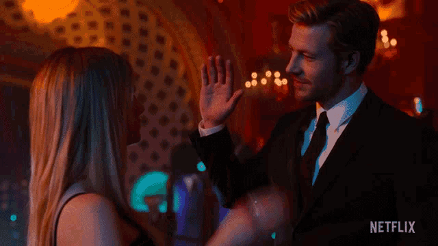 a man in a suit and tie is giving a woman a high five ..