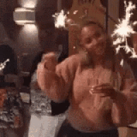 a woman is holding a glass of wine and sparklers in her hands .