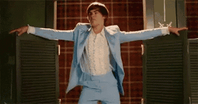 a man in a light blue suit is dancing in a room .