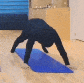a man is doing yoga on a blue mat in a living room .