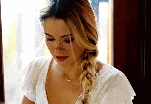 the woman is wearing a braided hairstyle and a white top