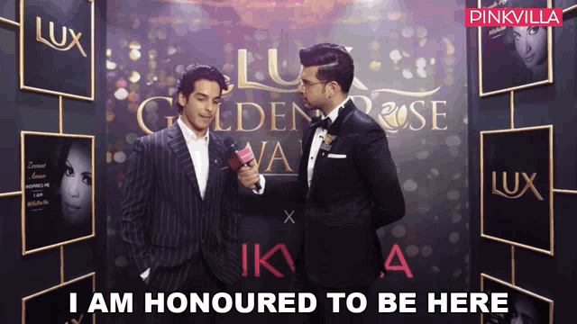 two men are standing in front of a wall that says lux on it