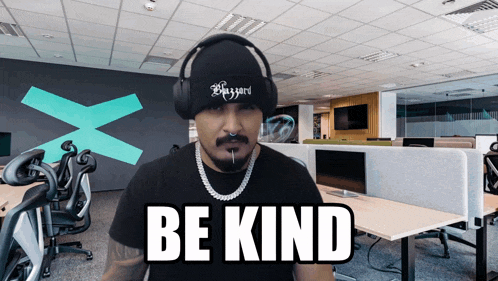 a man wearing headphones and a beanie with the word be kind on it