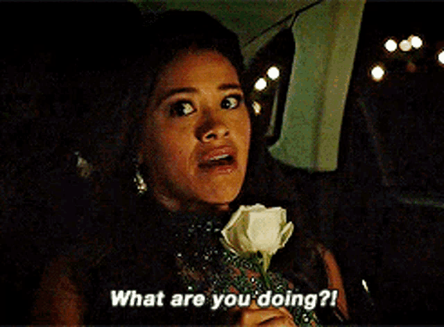 a woman is holding a white rose and saying what are you doing ?